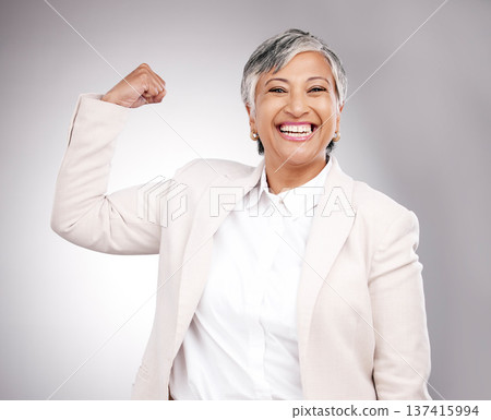 Strong, smile and portrait of businesswoman in a studio with strength or confidence gesture. Happy, excited and mature female model from Mexico flexing arm muscles for empowerment by gray background. Strong, smile and portrait of businesswoman in a studio with strength or confidence gesture. Happy, excited and mature female model from Mexico flexing arm muscles for empowerment by gray background. 137415994