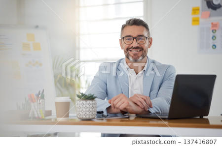 Portrait of businessman at office desk with smile, laptop and tablet on business website, online report or social media. Internet, digital app and confident, mature man with workshop and web schedule Portrait of businessman at office desk with smile, laptop and tablet on business website, online report or social media. Internet, digital app and confident, mature man with workshop and web schedule 137416807
