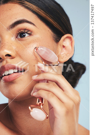Skincare, derma roller and woman in studio with face massage for wellness, anti aging or circulation on grey background. Crystal, facelift and beauty model with rose quartz lymphatic drainage facial Skincare, derma roller and woman in studio with face massage for wellness, anti aging or circulation on grey background. Crystal, facelift and beauty model with rose quartz lymphatic drainage facial 137417497