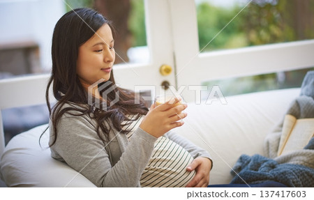 Pregnant woman, thinking or relax in house with tea, touch stomach or contemplation for motherhood. Future mom, pregnancy or herbal beverage in home with vision, reflection or love for unborn child Pregnant woman, thinking or relax in house with tea, touch stomach or contemplation for motherhood. Future mom, pregnancy or herbal beverage in home with vision, reflection or love for unborn child 137417603
