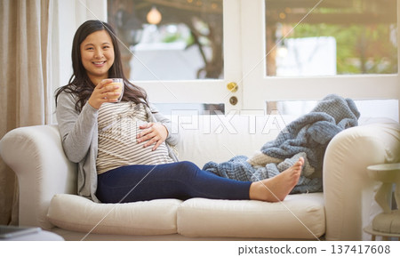 Portrait, pregnant woman and relax in home with coffee, peace and touch stomach on weekend break. Happy, female person and beverage in living room with pregnancy, rub belly and ready for motherhood. Portrait, pregnant woman and relax in home with coffee, peace and touch stomach on weekend break. Happy, female person and beverage in living room with pregnancy, rub belly and ready for motherhood. 137417608