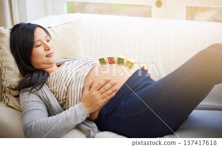 Relax, building blocks and future with pregnant woman on sofa in home for growth, baby news and love. Pregnancy announcement, wooden toys and support with person and belly in living room of apartment Relax, building blocks and future with pregnant woman on sofa in home for growth, baby news and love. Pregnancy announcement, wooden toys and support with person and belly in living room of apartment 137417618