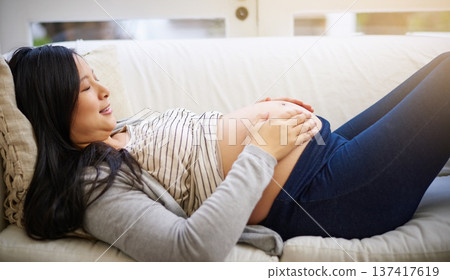 Happy, relax and pregnant woman on sofa with stomach for maternity health, wellness and rest. Pregnancy, home and person holding belly for calm, comfort and bonding for motherhood, love and parenting Happy, relax and pregnant woman on sofa with stomach for maternity health, wellness and rest. Pregnancy, home and person holding belly for calm, comfort and bonding for motherhood, love and parenting 137417619