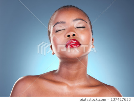 Glow, beauty and black woman with makeup, cosmetics and spa facial on a blue studio background. Shine, African person and model with lip gloss and aesthetic with dermatology, skincare and luxury Glow, beauty and black woman with makeup, cosmetics and spa facial on a blue studio background. Shine, African person and model with lip gloss and aesthetic with dermatology, skincare and luxury 137417633