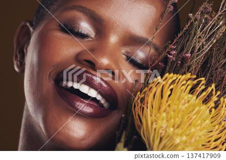 Skincare, beauty and plant with the face of a black woman in studio on brown background for natural treatment. Smile, protea or cosmetics and a young model indoor for aesthetic wellness with flowers Skincare, beauty and plant with the face of a black woman in studio on brown background for natural treatment. Smile, protea or cosmetics and a young model indoor for aesthetic wellness with flowers 137417909