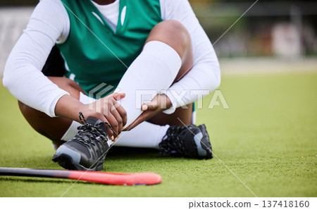 Hockey, pain and leg injury by woman player on a field with problem, joint or muscle crisis in sport. Hand holding, ankle and athlete with emergency, inflammation or fitness accident from training Hockey, pain and leg injury by woman player on a field with problem, joint or muscle crisis in sport. Hand holding, ankle and athlete with emergency, inflammation or fitness accident from training 137418160