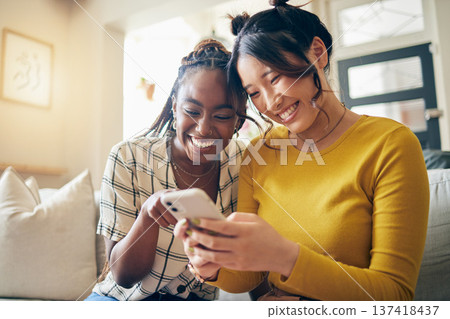Young women, funny meme and smartphone, friends relax at home with social media and communication. Gen z, happiness and comedy online, chat and using phone with people on couch, mobile app and tech 137418437