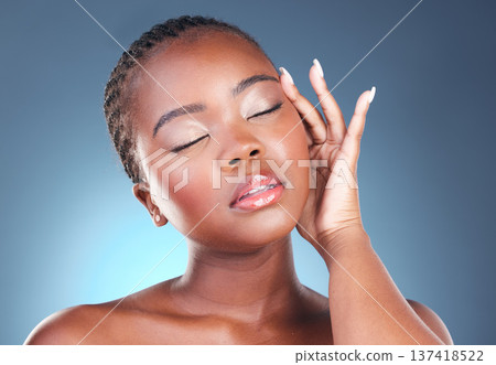 Skin, beauty and face of a black woman with makeup, dermatology and glow. Headshot of African person on a studio blue background with cosmetics and facial self care with hand for soft touch and shine Skin, beauty and face of a black woman with makeup, dermatology and glow. Headshot of African person on a studio blue background with cosmetics and facial self care with hand for soft touch and shine 137418522