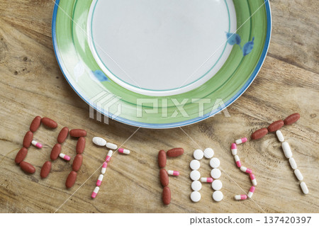 eat fast message with pills and half plate of food on table eat fast message with pills and half plate of food on table 137420397