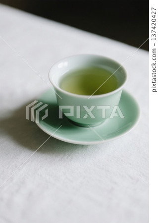 浅绿色茶杯与茶碟装盛绿茶 137420427