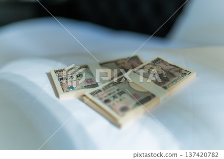 A stack of bills placed on a white bed A stack of bills placed on a white bed 137420782