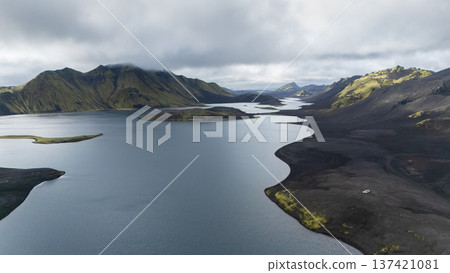 Aerial view on huge volcanic lake with approaching tiny cars and mountains in backdrop, Iceland 137421081