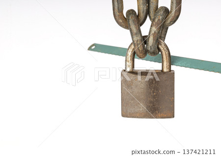 Close-Up of Rusty locked Padlock with Iron Chains and Green Hacksaw Blade on White Isolated Background Representing Security and Vulnerability Close-Up of Rusty locked Padlock with Iron Chains and Green Hacksaw Blade on White Isolated Background Representing Security and Vulnerability 137421211