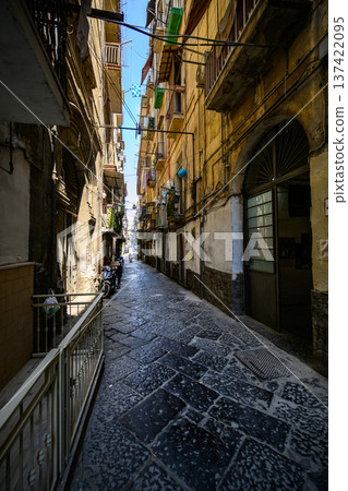 Traditional alley in the historic district of Naples, Italy with aged facades, balconies and narrow urban space. Classic example of Mediterranean architecture and authentic street atmosphere found in  137422095