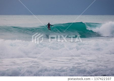 Surfer and barrel ocean wave in sea. Surfing lifestyle and extreme water sport concept. 137422107