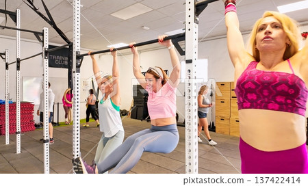 Women lifting body weight doing kippings in gym Women lifting body weight doing kippings in gym 137422414