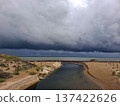 The Mediterranean Sea shows layered low clouds before Hurricane Dana. A stream flows into the sea while sandy beach stretches on the shore. People may be preparing for the storm. 137422626