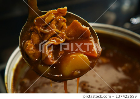 Scooping up pork curry from a hot pot 137422659