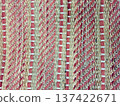 This macro shot captures the intricate details of a hand woven ethnic rug. It highlights organic jute fibers mixed with bold red wool stripes, showcasing craftsmanship and texture. 137422671