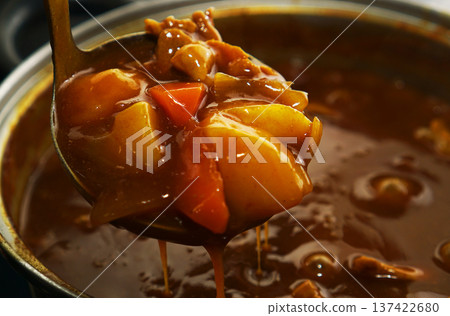 Scooping up pork curry from a hot pot Scooping up pork curry from a hot pot 137422680