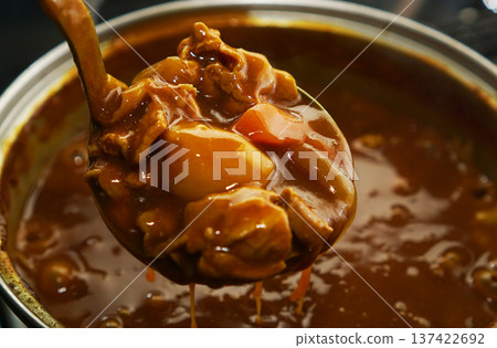 Scooping up pork curry from a hot pot 137422692