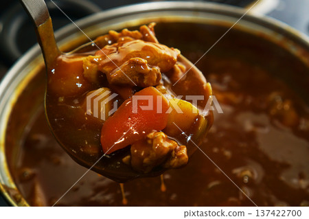 Scooping up pork curry from a hot pot 137422700