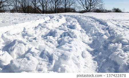 Deep vehicle tracks in the snow after a heavy snowfall. Snowplow tire tracks in the snow on a sunny winter day. Deep vehicle tracks in the snow after a heavy snowfall. Snowplow tire tracks in the snow on a sunny winter day. 137422878