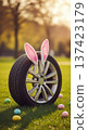 Tire wheel bunny ears Easter eggs grass spring auto holiday display on lawn, playful seasonal car service concept. 137423179