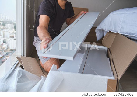 Man assembling flat pack furniture in new apartment 137423402
