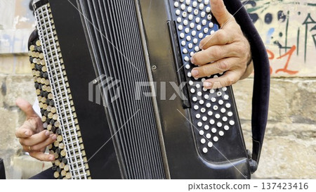 Male hands of musician playing the accordion at urban street. The detailed view highlights texture of instrument, capturing rhythm, tradition, and the expressive character of live music performance Male hands of musician playing the accordion at urban street. The detailed view highlights texture of instrument, capturing rhythm, tradition, and the expressive character of live music performance 137423416