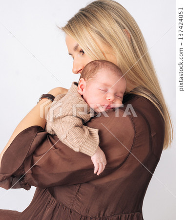 Woman holding her infant baby close to her chest. Warm moment of parenthood and baby care.  137424051
