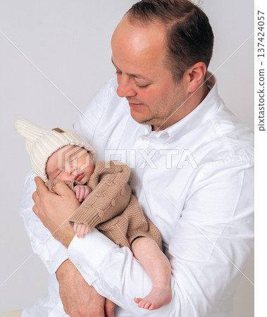 Father gently holding and looking at his sleeping newborn baby. Tender moment of fatherhood.  137424057