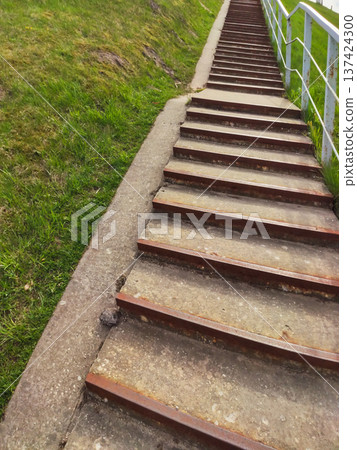 A staircase outdoors with a green field in the background. Journey and peaceful nature atmosphere. 137424300
