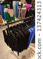 A modern clothing store with racks of stylish apparel. Trendy fashion and curated retail space. 137424313