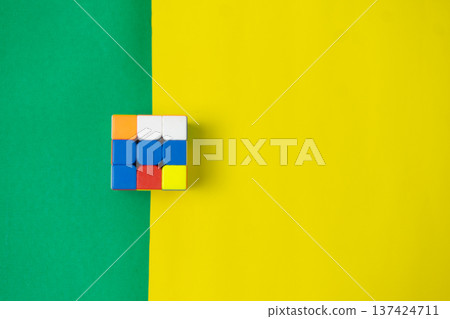Colorful Puzzle Cube on Vibrant Green and Yellow Background 137424711