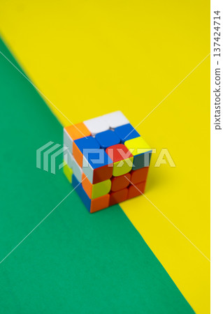 Colorful Puzzle Cube on Bright Yellow and Green Background 137424714