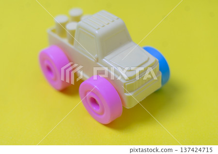 Colorful Plastic Toy Truck with Pink Wheels on Yellow Background Colorful Plastic Toy Truck with Pink Wheels on Yellow Background 137424715