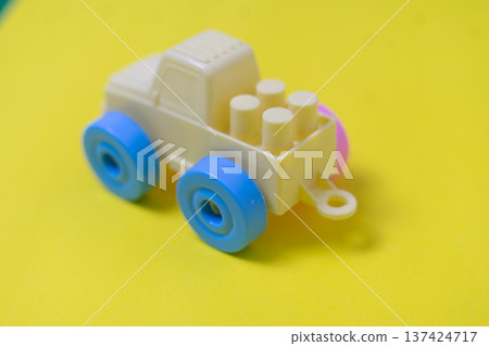 Cream Plastic Toy Truck with Blue Wheels on Yellow Background Cream Plastic Toy Truck with Blue Wheels on Yellow Background 137424717