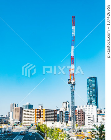 Construction cranes and urban buildings towering against the blue sky Construction cranes and urban buildings towering against the blue sky 137426958