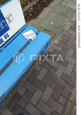A white handkerchief forgotten on a blue bench at the bus stop A white handkerchief forgotten on a blue bench at the bus stop 137427676