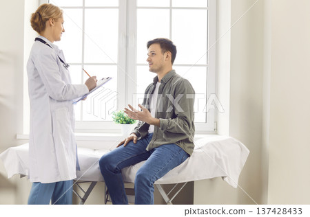 Patient explains health problems and attentive doctor writes down information during consultation. 137428433