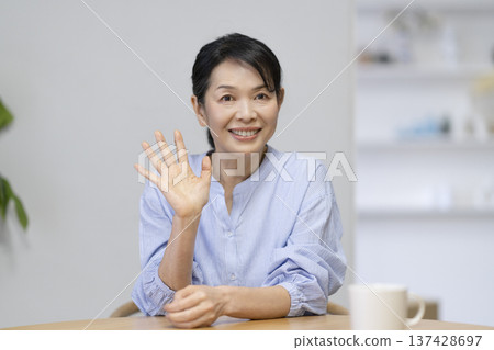 A woman in her late 50s waving at the camera 137428697