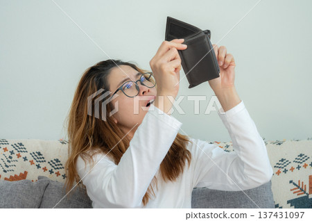 Asian woman trying to find money in her empty wallet. Having financial problems means being unable to pay debts over the short or long term. 137431097