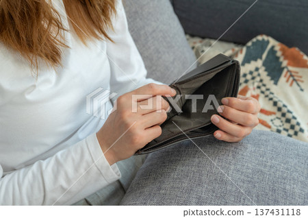 Cropped shot view of woman holding and showing her empty wallet. Having financial problems means being unable to pay debts over the short or long term. 137431118
