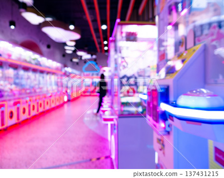 Blurred Motion of People Walking Past Colorful Neon Arcade Game Machines with Red and Blue LED Lights 137431215