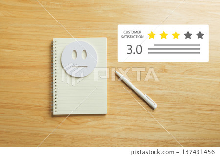 Form for customer survey reveals satisfaction review, feedback collected with neutral face on spiral notebook, pen on wooden table showing 3.0 rating for service experience evaluation Form for customer survey reveals satisfaction review, feedback collected with neutral face on spiral notebook, pen on wooden table showing 3.0 rating for service experience evaluation 137431456