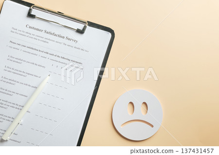 Form for customer satisfaction survey on clipboard with pen awaits feedback, allowing rating review of service quality, reflecting negative experience with sad face icon Form for customer satisfaction survey on clipboard with pen awaits feedback, allowing rating review of service quality, reflecting negative experience with sad face icon 137431457