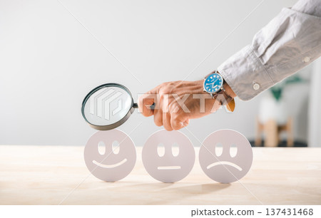Satisfaction, customer business quality survey face rating, magnifying glass held by hand, examining feedback icons for positive service assessment 137431468