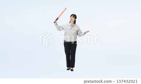 Full-body photo of a woman in work clothes holding an exit light and guiding 137432021