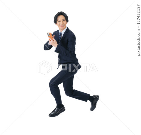 一位男性商務人士一邊跳躍一邊使用智慧型手機。全身PNG格式照片，背景透明，手工精準摳圖。 137432157